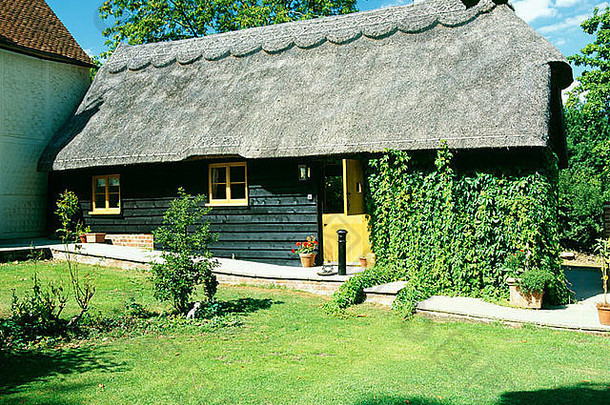 小型转换谷仓的茅草屋顶，黑色木结构墙