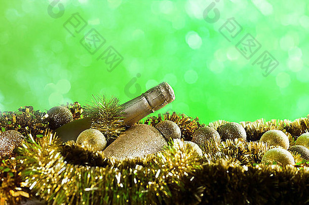 绿色背景上的香槟酒瓶和金色圣诞装饰