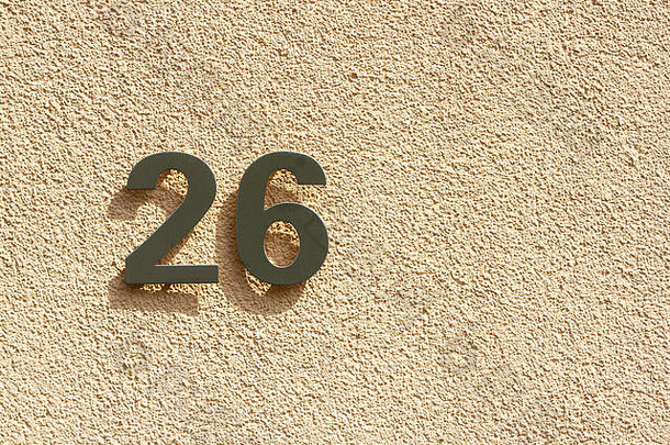 26号房子的26个<strong>银色</strong>金属数<strong>字</strong>在浅橙色的石膏墙上投下了阴影