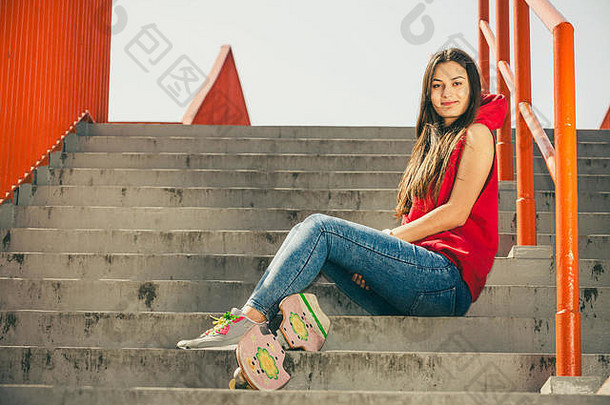 很酷的溜冰者年轻的长头发的女孩滑板坐着城市楼梯活跃的生活方式时髦的夏天户外时尚的体育运动十几岁的