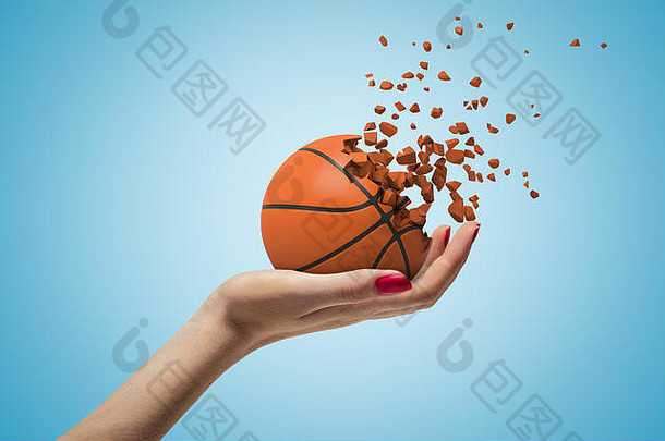 女手持有篮球球粉碎块蓝色的背景