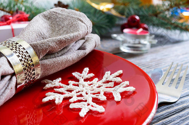 圣诞餐桌布置。黑色木质背景上圣诞树的红色盘子、叉子、刀、蜡烛、餐巾纸、礼品枝。空间。圣诞节X