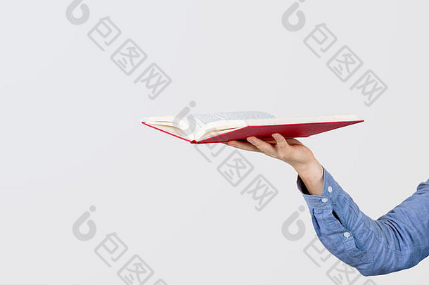 少年手拿着一本打开的书，背景是白色的。
