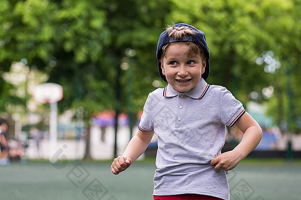年轻快乐的小男孩微笑着在公园里问候某人