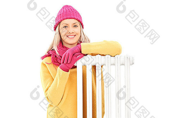 年轻的女人冬天衣服坐着散热器