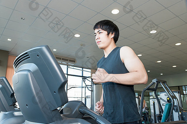 亚洲年轻人在健身房跑步机上跑步