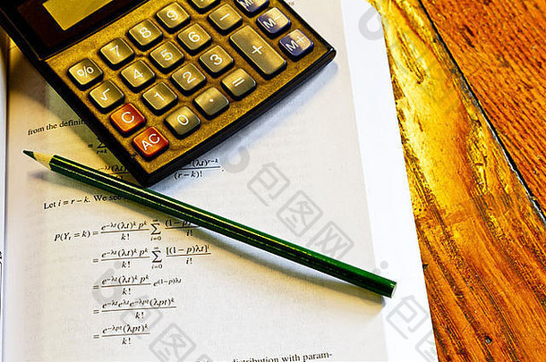 橡木桌上的计算器、铅笔和数学书建议做预算工作或家庭作业。