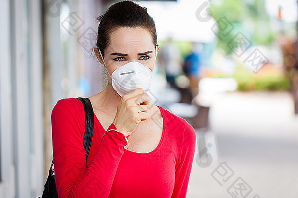 一个戴着口罩的女人在城里咳嗽。