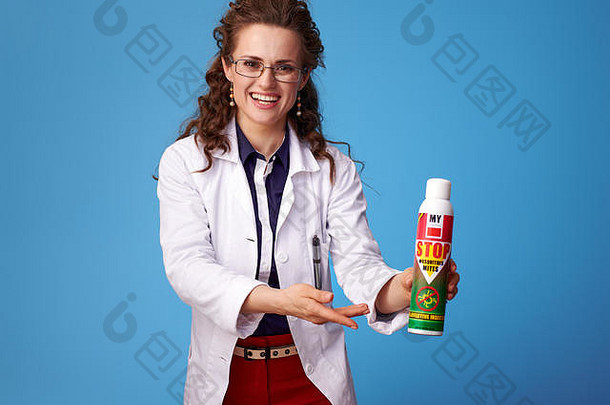 穿着白色医疗袍的快乐女医生在蓝色背景下展示杀虫剂