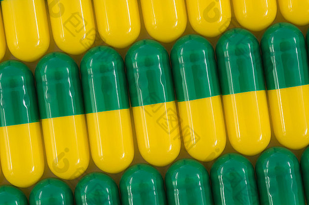 药丸特写-胶囊形式制成的明胶。绿色/黄色药丸。比喻在高药价问题上与美国制药公司较量。