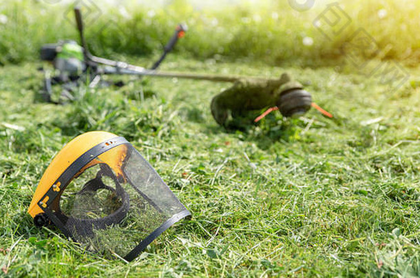 修剪过的草上的线状修剪器和防护面罩，在背景上种植草，banner 16x9格式