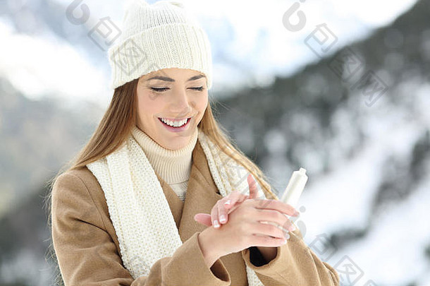 冬天雪山上的快乐女人用保湿霜滋润双手肌肤
