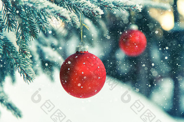 降雪时挂在树上的红色圣诞饰品的特写镜头。这张照片是在芬兰的卡里纳拍摄的。