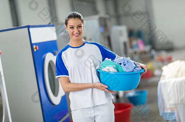 微笑女人持有洗衣篮子清洁衣服