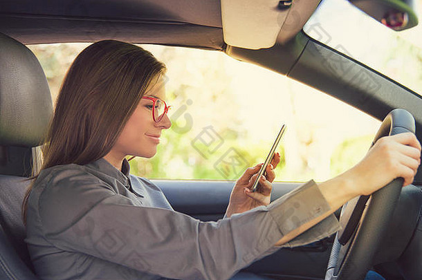 一边视图心烦意乱年轻的女人眼镜智能手机开车车