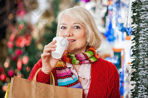 在圣诞商店拿着购物袋喝咖啡的女人