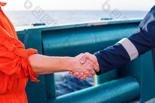 海事承包商商人与船上工人握手。