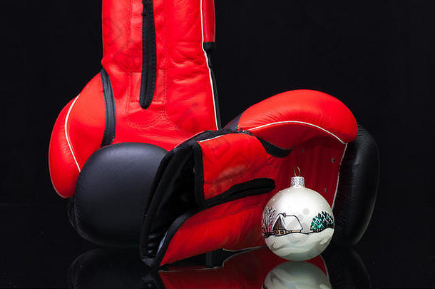 红色和黑色拳击手套和黑色玻璃桌上的圣诞装饰。圣诞节不是争夺圣诞礼物的斗争。