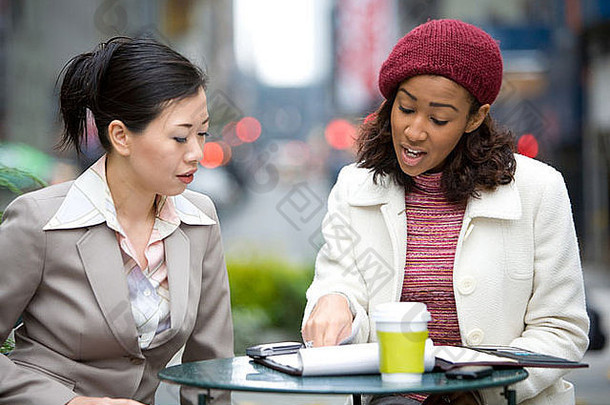两位女商人在城市里随意会面或讨论。
