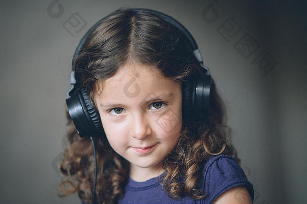 美丽快乐的<strong>小卷发</strong>女孩戴着耳机听音乐