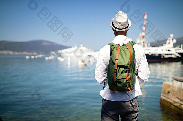 度假，度假，旅游，海洋和人的概念。背着背包享受旅行的男人