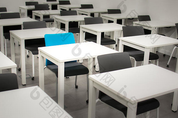 教室里有黑色的椅子和一把蓝色的椅子。招聘、空缺或选择概念。白色书桌
