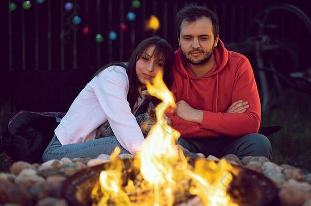 肖像快乐可爱的夫妇坐着火秋天晚上