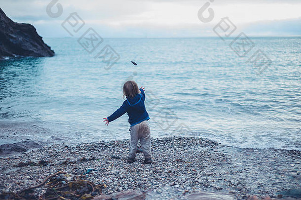 一个蹒跚学步的小孩正在往海里扔石头