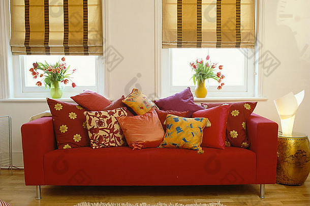 宽带材米色百叶窗窗户红色的沙发堆色彩斑斓的丝绸垫子现代生活房间