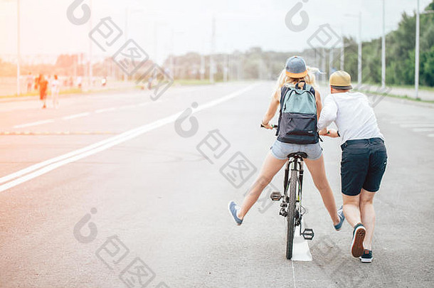 女孩自行车的家伙运行男孩教女孩骑自行车早....草地
