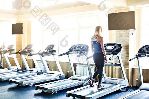 在健身房锻炼的年轻女子。在机器上运行。