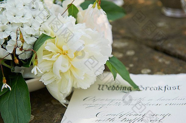 羊皮纸上的书法菜单上有来自猫头鹰庄园风格婚礼拍摄的牡丹花