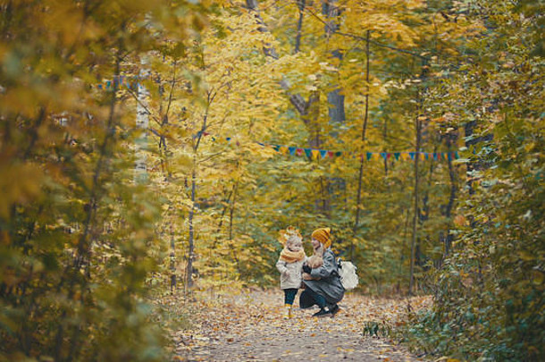 漂亮的女儿妈妈走秋天公园拥抱