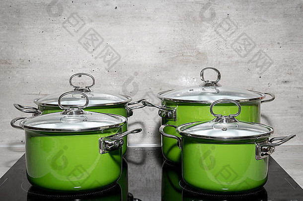 黑色电磁炉上的四个绿色搪瓷炖锅