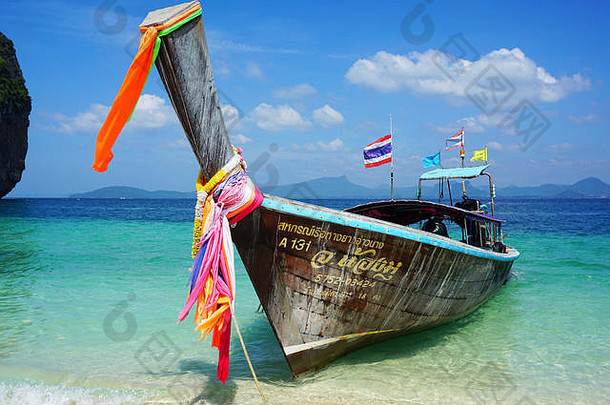 泰国传统的长尾船停靠在菲律宾群岛的海滩上。这艘船色彩鲜艳，外观独特，吸引了游客
