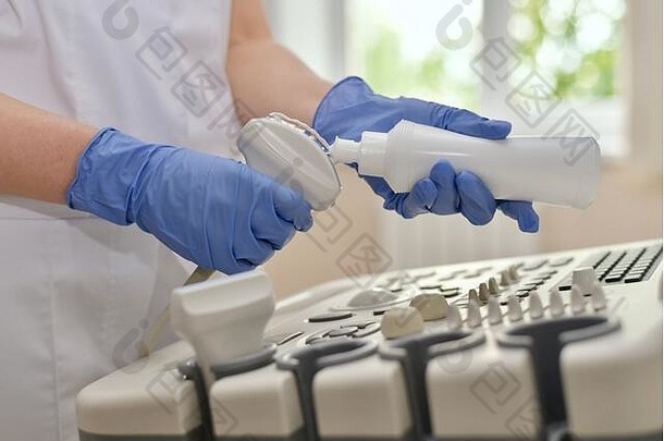 手戴手套，在超声波扫描仪传感器上涂抹一条透明凝胶。