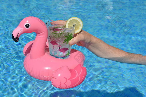 女人持有粉红色的火烈鸟充气喝持有人塑料杯装饰手掌火烈鸟片柠檬有趣的夏天共鸣