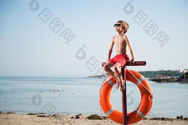 孩子红色的短裤太阳镜坐着海滩救生圈如此日光浴休闲活动