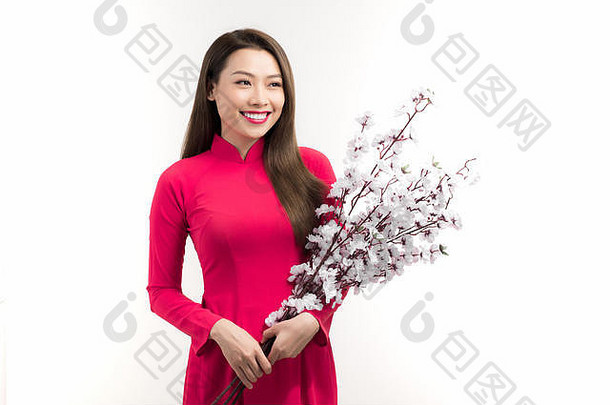 美丽的亚洲女人穿着越南传统的奥黛，在春节期间手持桃花。