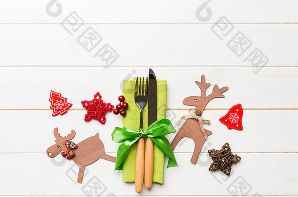 餐巾纸上新年用具的俯视图，带有节日装饰和木制背景上的驯鹿。圣诞晚餐的概念与空间。