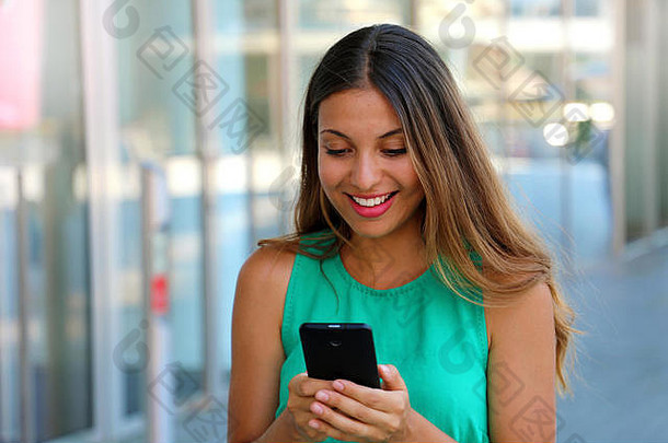 时尚女人智能手机站购物中心有吸引力的年轻的女人发短信享受购物一天