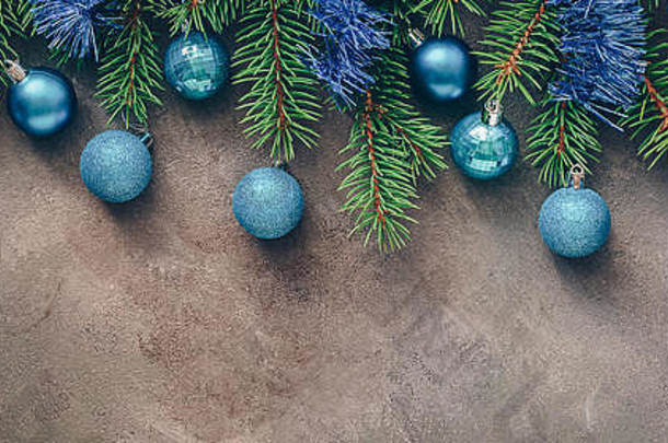 圣诞镶边，冷杉枝在深色质感的乡村背景上装饰着蓝色的球和金属箔。俯视图、平面布局、空间