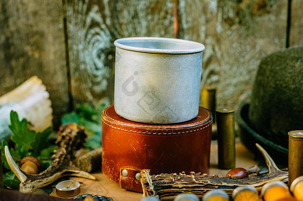 特写铝制马克杯，供参考，站在圆形狩猎盒上，放置狩猎或旅游古董装备。