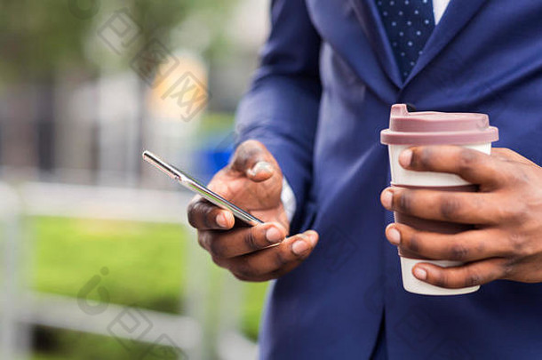 忙碌的商人在户外使用智能手机喝外卖咖啡
