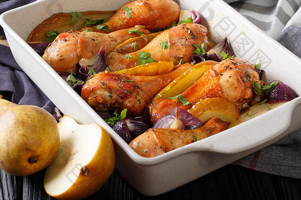 秋天的食物：用红洋葱、梨和香草做成的鸡腿放在盘子里烘烤。水平的
