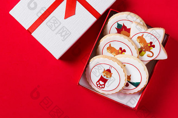 在红色背景上，用圣诞图案装饰在礼品盒中的圣诞黄油饼干。顶视图。