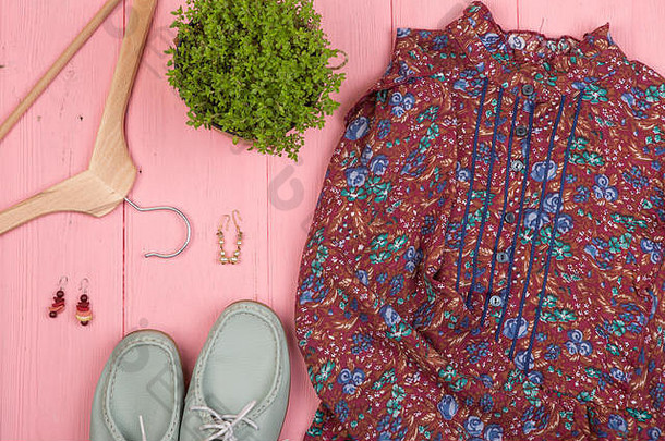 时尚趋势衣服花打印鞋子悬挂器花耳环粉红色的木桌子上