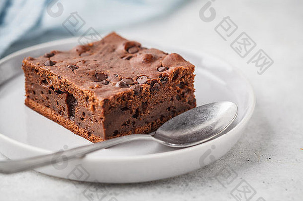 一块巧克力纯素蛋糕，上面有巧克力滴和坚果。