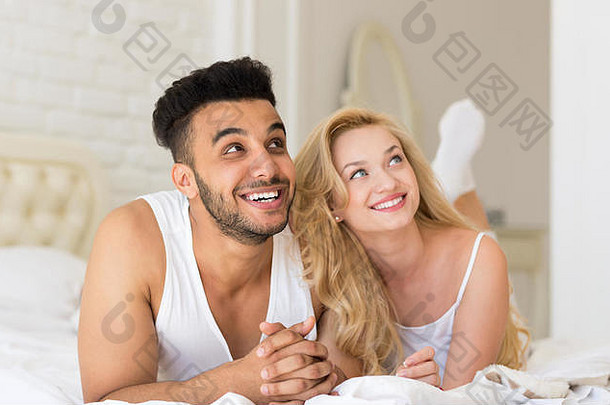 年轻夫妇躺在床上，<strong>幸福</strong>地微笑着，西班牙裔男女恋人在卧室里