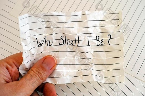 女人手里拿着皱巴巴的纸，上面写着“我是谁？”。特写。